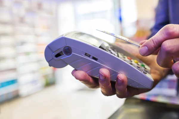 Hombre pagando con tecnología NFC en tarjeta de crédito, en farmacia — Foto de Stock