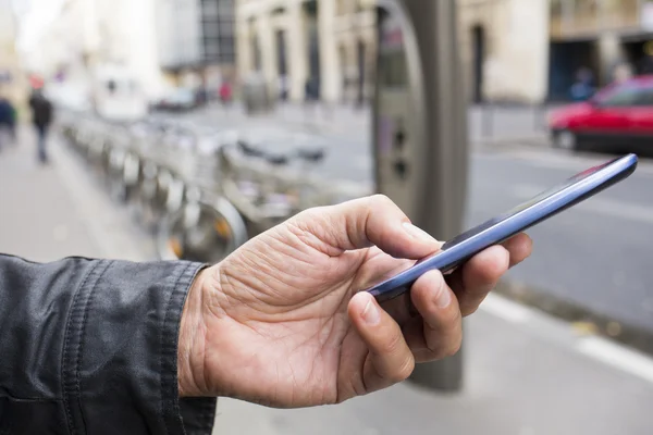 Hombre usando un teléfono móvil frente a la estación de Velib, París — Foto de Stock