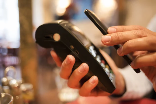 Hombre que paga con tecnología NFC en el teléfono móvil, en el restaurante, b —  Fotos de Stock