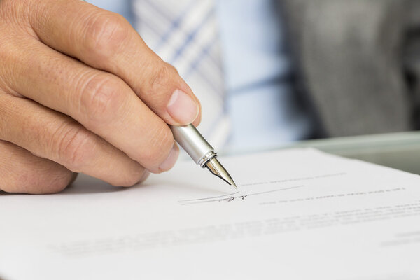 Бизнесмен подписывает контракт, сосредоточьтесь на ручке
