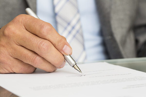 Бизнесмен подписывает контракт, сосредоточьтесь на ручке
