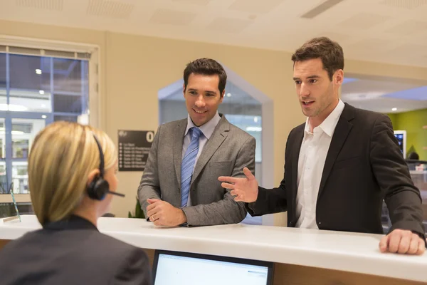 Zakenlieden communiceren met receptioniste — Stockfoto