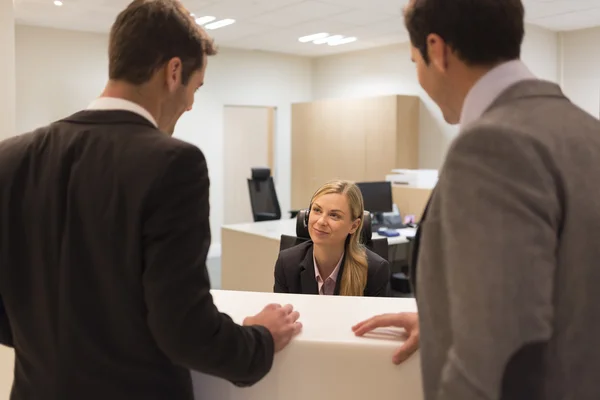Uomini d'affari che comunicano con la receptionist — Foto Stock