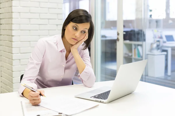 Depressed businesswoman sitting in office Stock Photo