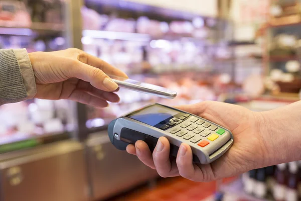 Mujer que paga con tecnología NFC en el teléfono móvil — Foto de Stock