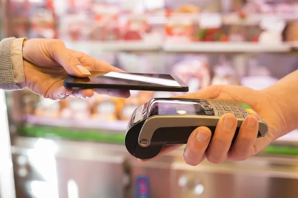 Mujer que paga con tecnología NFC en el teléfono móvil — Foto de Stock