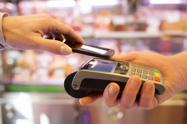 Woman paying with NFC technology on mobile phone — Stock Photo, Image