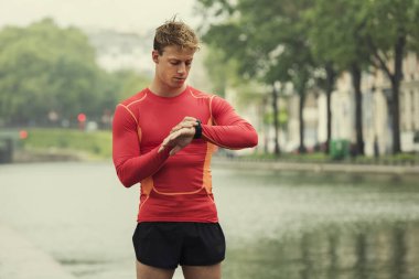 Genç koşan adam kalp atış hızına bakıyor spor monitörü akıllı saat.
