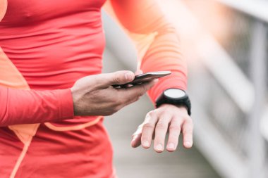 Koşan adam cep telefonu ve akıllı arama uygulamasında spor performansını kontrol ediyor.