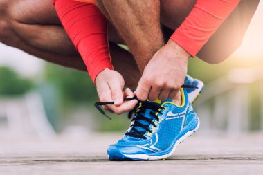 Runner tying his running shoes. City man shoelace sneakers