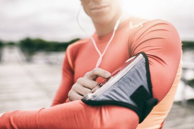 Açık hava koşucusu koşu sırasında mp3 çalarını ayarlıyor. Mercek parlaması