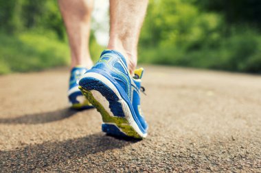 Closeup of running shoes in action on the road in forest.