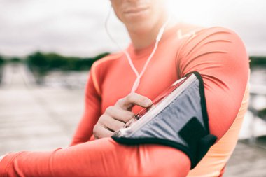 Açık hava koşucusu koşu sırasında müzik çalarını ayarlıyor. Mercek parlaması