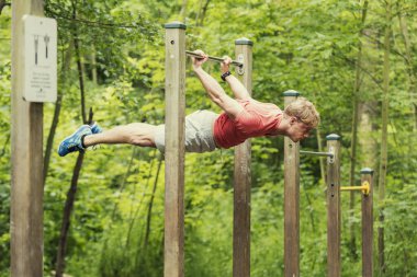 Parktaki barın üstünde şınav çeken erkek sporcu. Dışarıda çalış.