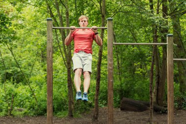 Parktaki barın üstünde şınav çeken erkek sporcu. Dışarıda çalış.