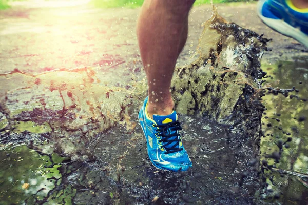 Su birikintisinde yürüyen, ayakkabılarını sıçratan bir adam. Kros yolu