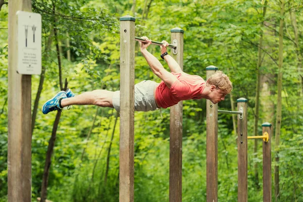 Parktaki barın üstünde şınav çeken erkek sporcu. Dışarıda çalış.