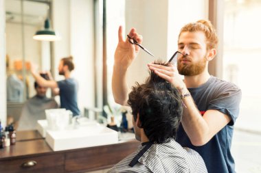 Adam berberinde saçını kestiriyor.