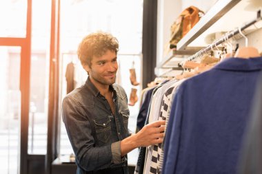 Adam giyim mağazasından alışveriş yapıyor.