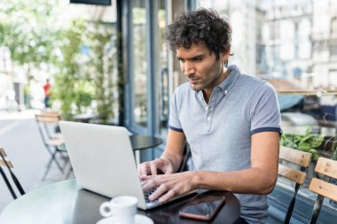 Kafe terasında dizüstü bilgisayarda çalışan genç serbest çalışan bir erkek. Şehirde bilgisayar kullanan bir iş adamı.
