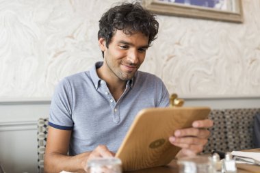 Modern bir restoranda menüsü olan neşeli bir adam.