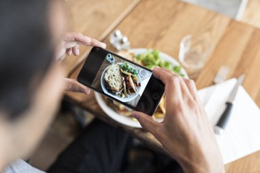 Close-up of hands male in the restaurant taking picture food with his smart phone