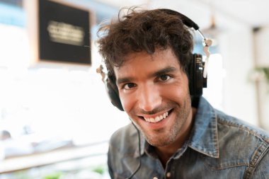Neşeli bir adamın portresi kulaklıkla müzik dinliyor. Kameraya bakıyorum.