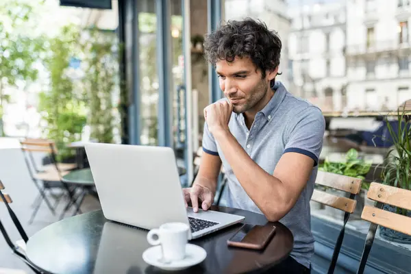 Kafe terasında dizüstü bilgisayarda çalışan genç serbest çalışan bir erkek. Şehirde bilgisayar kullanan bir iş adamı.