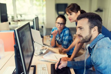Orta yaşlı kadın menajer modern bir ofiste ekibiyle birlikte çalışıyor.