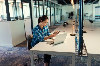 Modern ofis yerinde uygulamalı cep telefonuyla mesajlaşan hoş bir kadın..