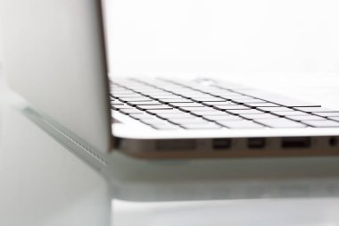 Laptop on modern glass table in office. Focus on keyboard