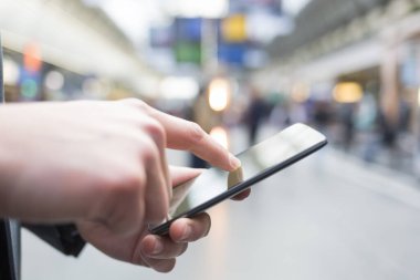 İstasyonda cep telefonunu kullanan bir adam var. Eller yakın çekim.