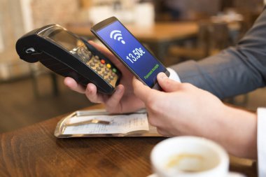 NFC teknolojisiyle ödeme yapan adam cep telefonuyla, restoranda, barda, kafede. Euro Fransızca versiyonu