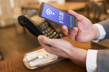 NFC teknolojisiyle ödeme yapan adam cep telefonunda, restoranda, barda, kafede
