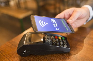Cep telefonunda NFC teknolojisiyle ödeme yapan adam. Pound English versiyonu. Hareketli el