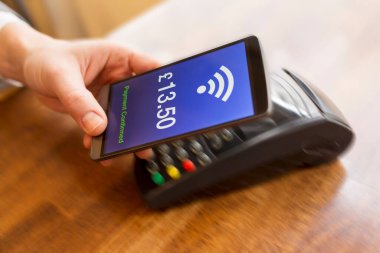 Cep telefonunda NFC teknolojisiyle ödeme yapan adam. Livre İngilizce versiyonu. Hareketli el