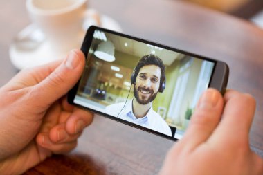 Bir akıllı telefon sırasında bir skype video tutan bir erkek el closeup