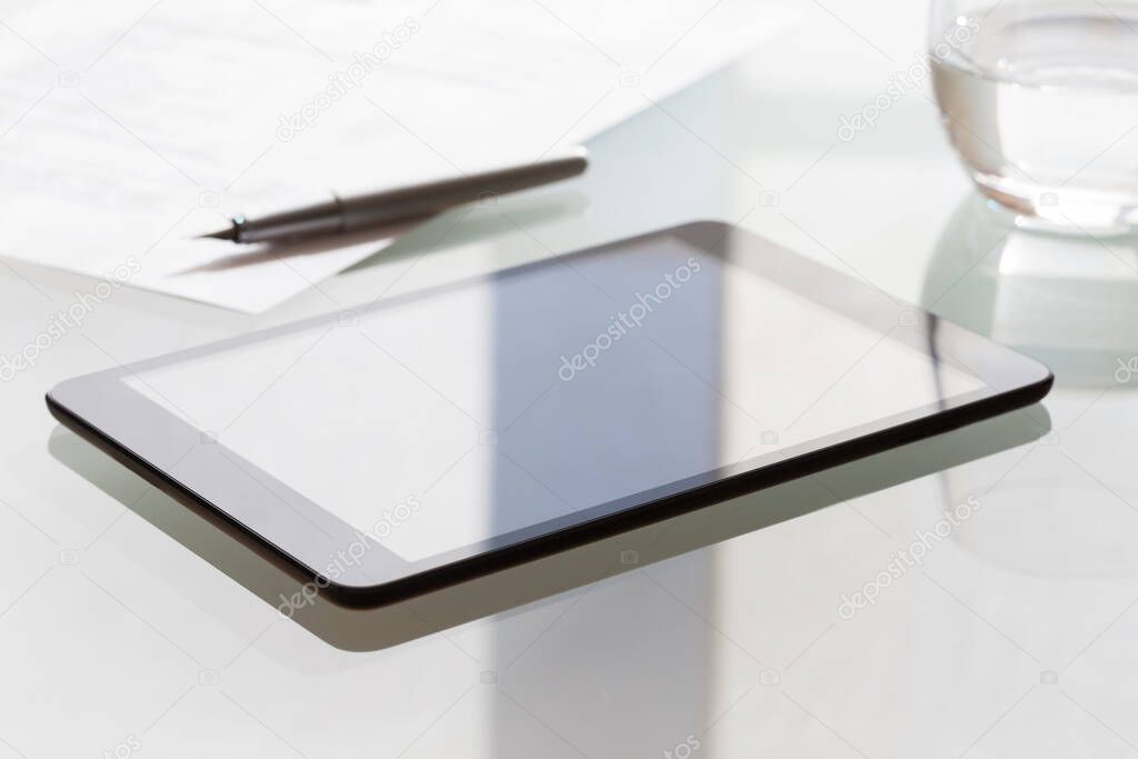 Digital tablet on modern glass table in office