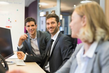 Modern bir ofiste bilgisayar üzerinde çalışan bir grup iş adamı.