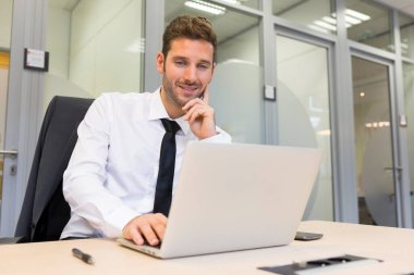 Modern ofiste bilgisayar üzerinde çalışan bir iş adamı