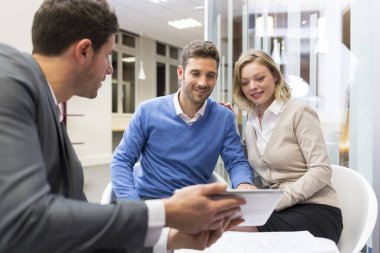 Young couple meeting real-estate showing a house project on a di