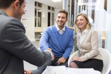 Young couple shaking hand real-estate agent in agency office