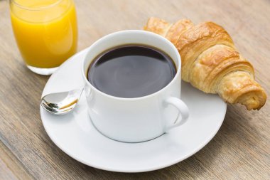 Bir fincan sade kahve ve kruvasanla kahvaltı.