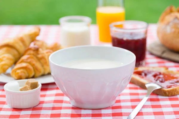 Breakfast with milk, orange juice, croissant, marmalade and brea