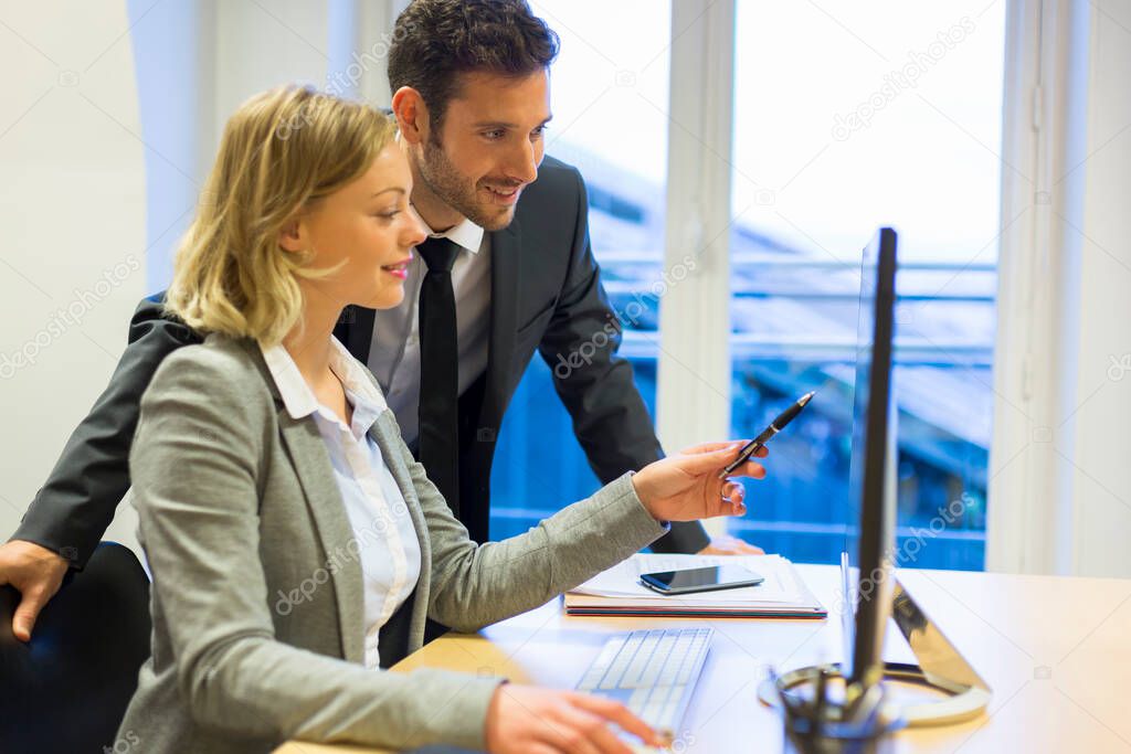 Two business people in a office, working on computer