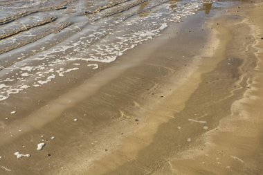 Kumsalda küçük dalgalar ve köpükler. Littlehampton, Batı Sussex, İngiltere