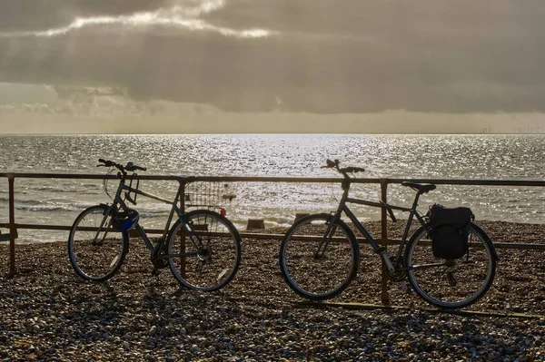 Two Bicycles Leaning Railings Shingle Beach Stormy Sky Shimering Sea — Stock fotografie