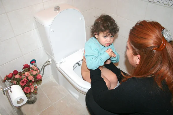 Mamma sätter barnet i toal — Stockfoto