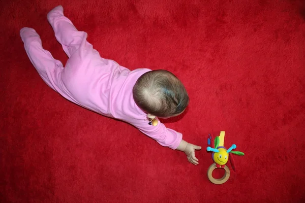 Baby trying to reach her toy — Stock Photo, Image