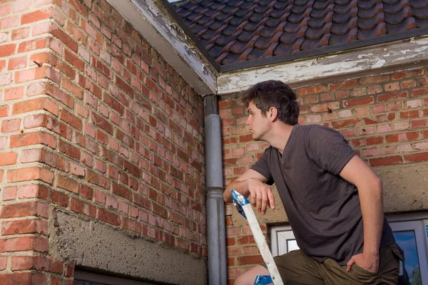 Young man inspecting the wall of an old house — Stock Photo, Image